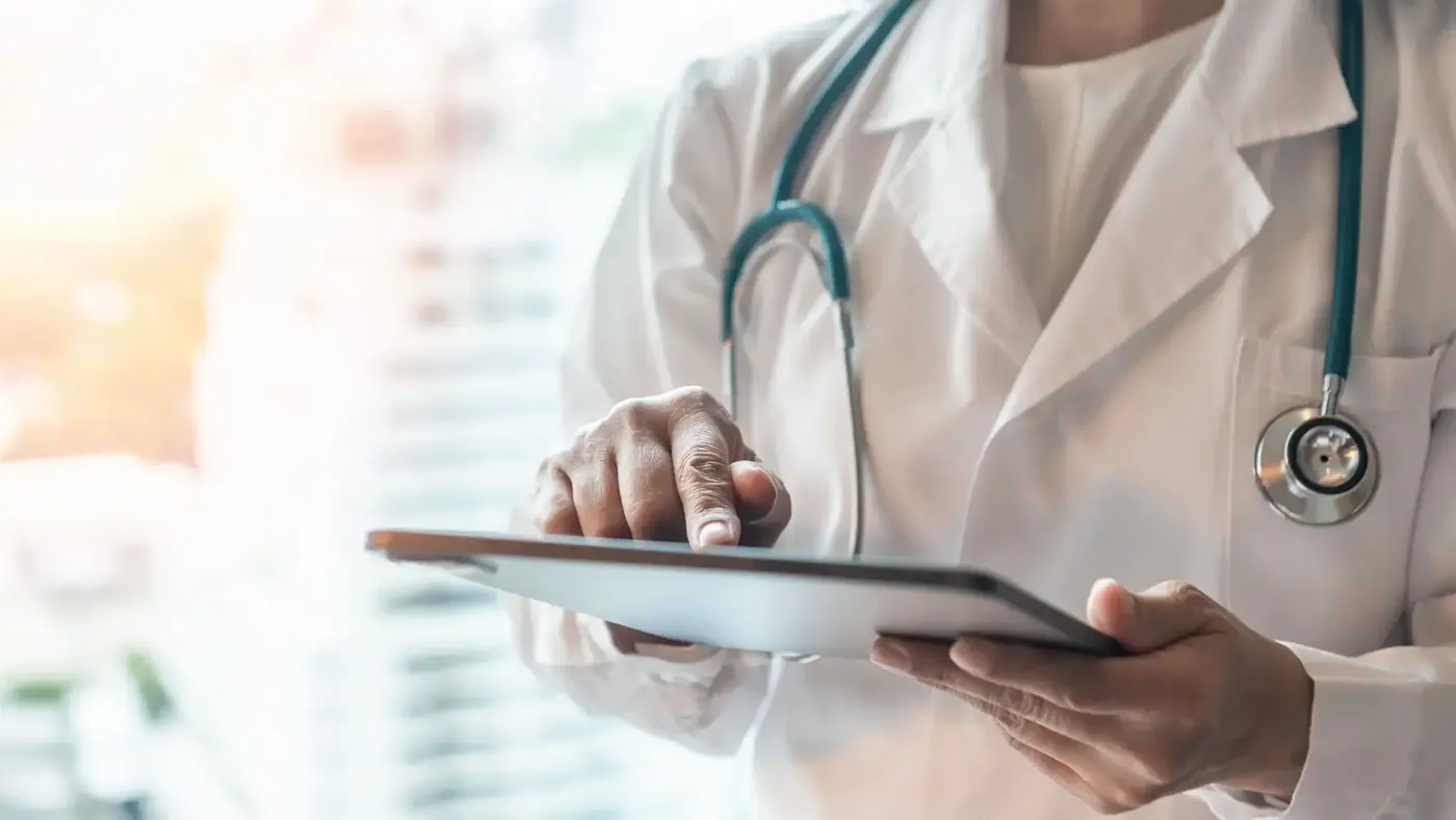Doctor reviewing notes on a tablet during a consultation