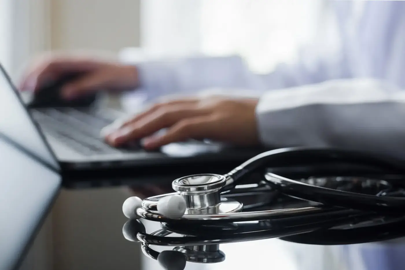 Psychiatrist typing an independent report with a stethoscope on the desk